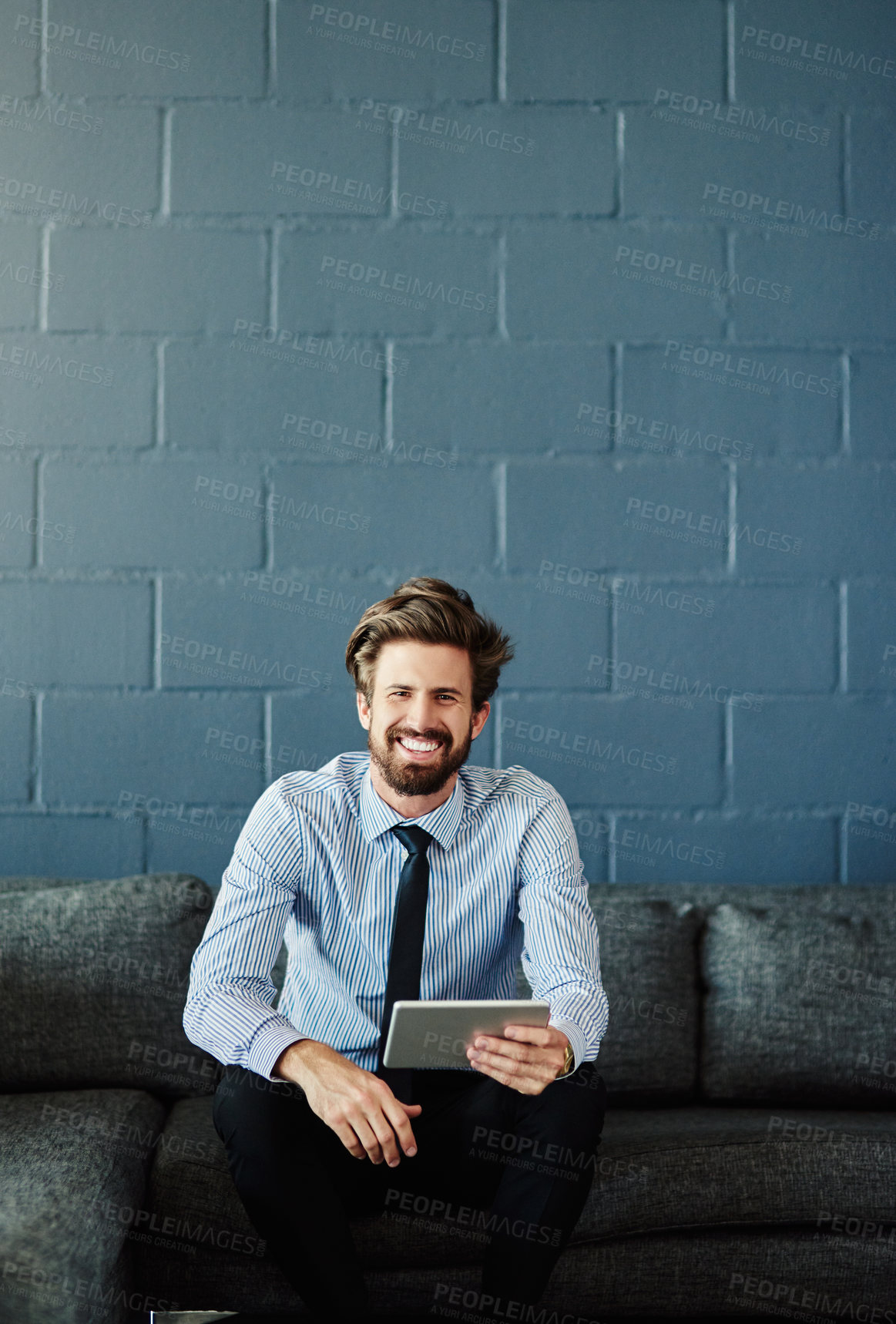 Buy stock photo Cropped portrait of a handsome young businessman using his digital tablet in the office