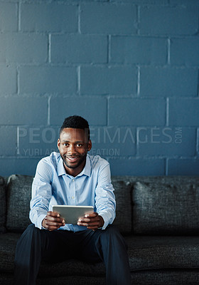 Buy stock photo Cropped portrait of a handsome young businessman using his tablet while sitting on a sofa in the office