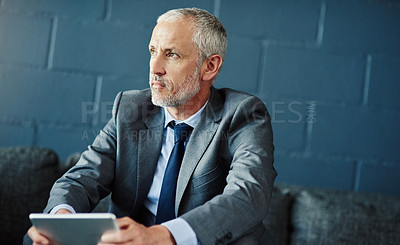 Buy stock photo Cropped shot of a handsome and thoughtful mature businessman using a digital tablet in his office
