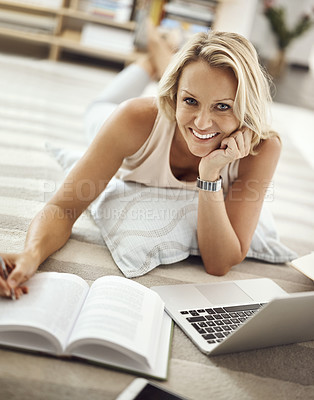 Buy stock photo Cropped portrait of a beautiful mature woman lying on her living room floor doing some research