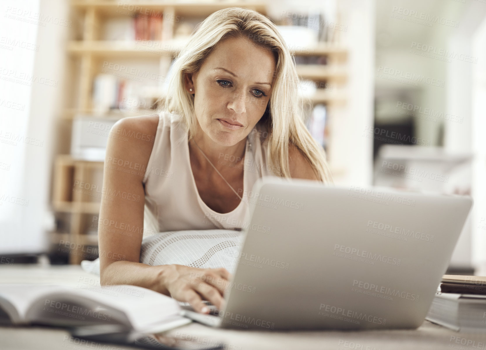 Buy stock photo Cropped shot of a beautiful mature woman lying on her living room floor using a laptop