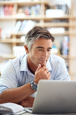 Buy stock photo Cropped shot of a handsome mature man lying on his living room floor using a laptop