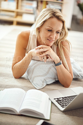 Buy stock photo Cropped shot of a beautiful mature woman lying on her living room floor using a laptop