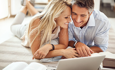 Buy stock photo Cropped shot of an affectionate mature couple lying on their living room floor doing some online research