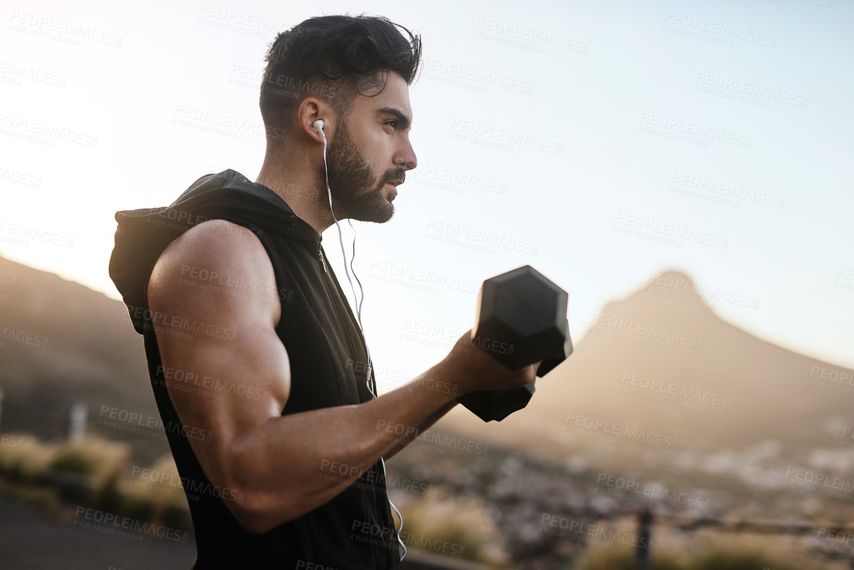 Buy stock photo Shot of a sporty young man exercising with weights outdoors