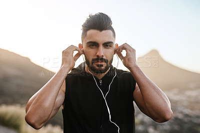 Buy stock photo Portrait of a young man listening to music while exercising outdoors
