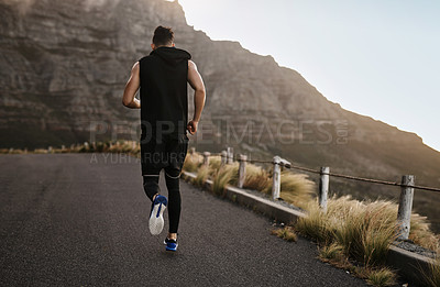 Buy stock photo Rearview shot of a sporty young man exercising outdoors