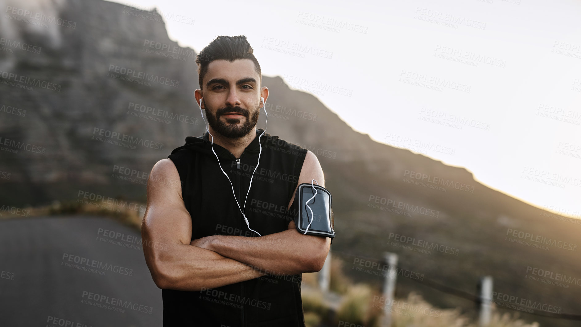 Buy stock photo Man, portrait and arms crossed for mountain fitness, earphones and outdoor road for challenge. Male person, sports workout and cardio for marathon training, athlete and streaming sound for exercise