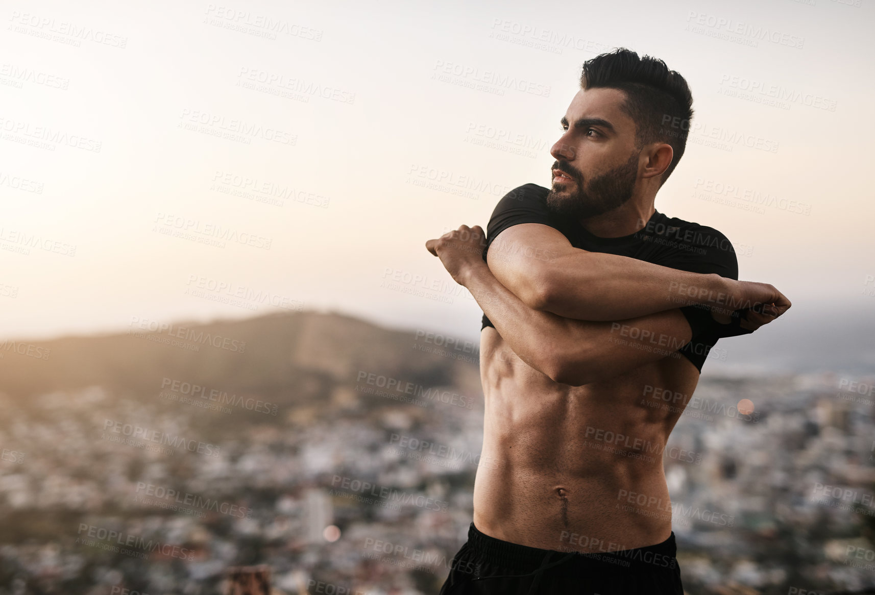 Buy stock photo Shot of a sporty young man lifting up his top while exercising outdoors