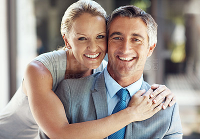 Buy stock photo Cropped portrait of a smiling mature business couple hugging each other closely and smiling at the camera