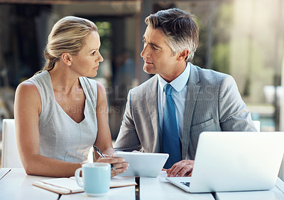 Buy stock photo Shot of a focused mature business couple looking at each other and thinking of their next move in the office