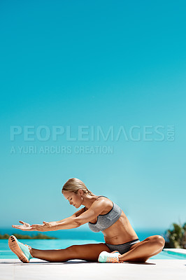 Buy stock photo Shot of an attractive young woman in gym wear stretching by the pool after her workout on a sunny day