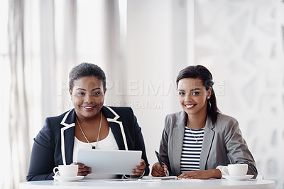 Buy stock photo Cropped portrait of two attractive young businesswomen working together behind a desk in their office