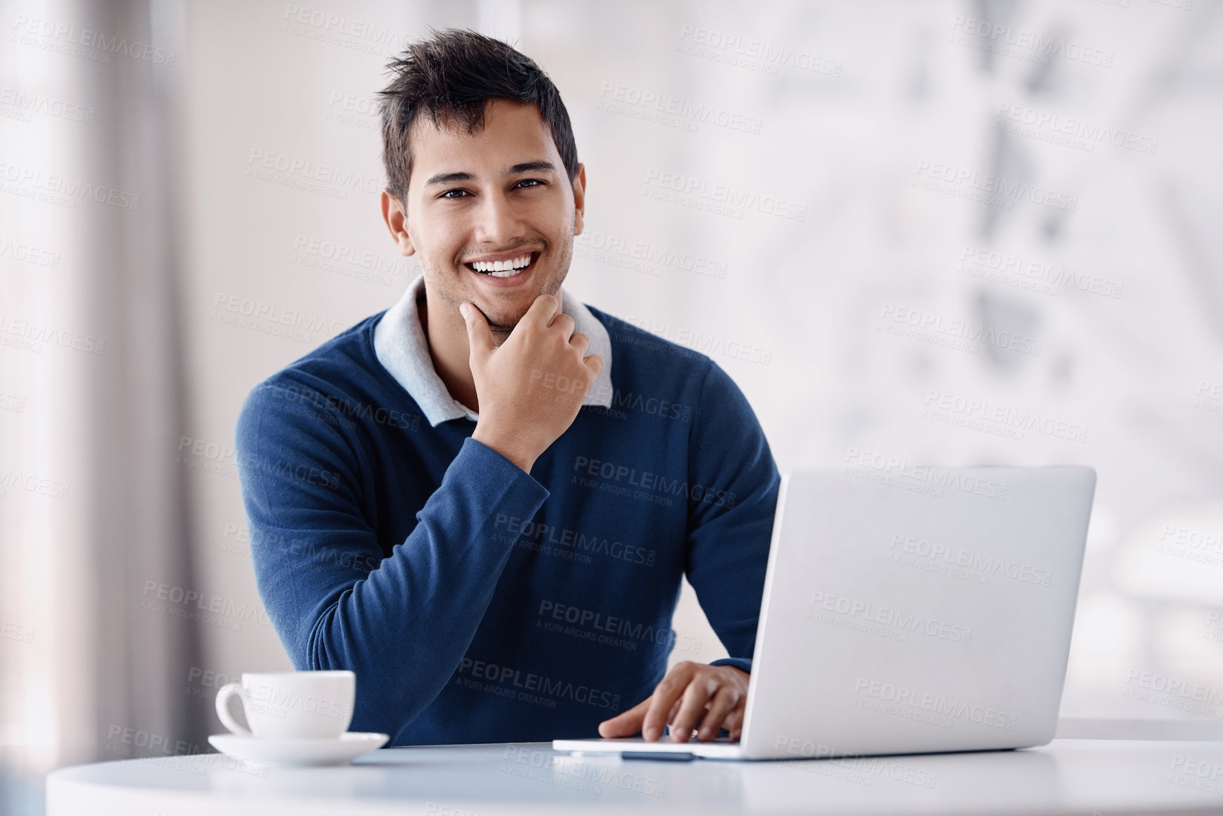 Buy stock photo Cropped portrait of a handsome young businessman looking thoughtful while working on his laptop in the office