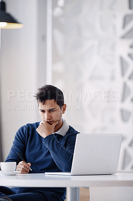 Buy stock photo Cropped shot of a handsome young businessman looking thoughtful while working on his laptop in the office