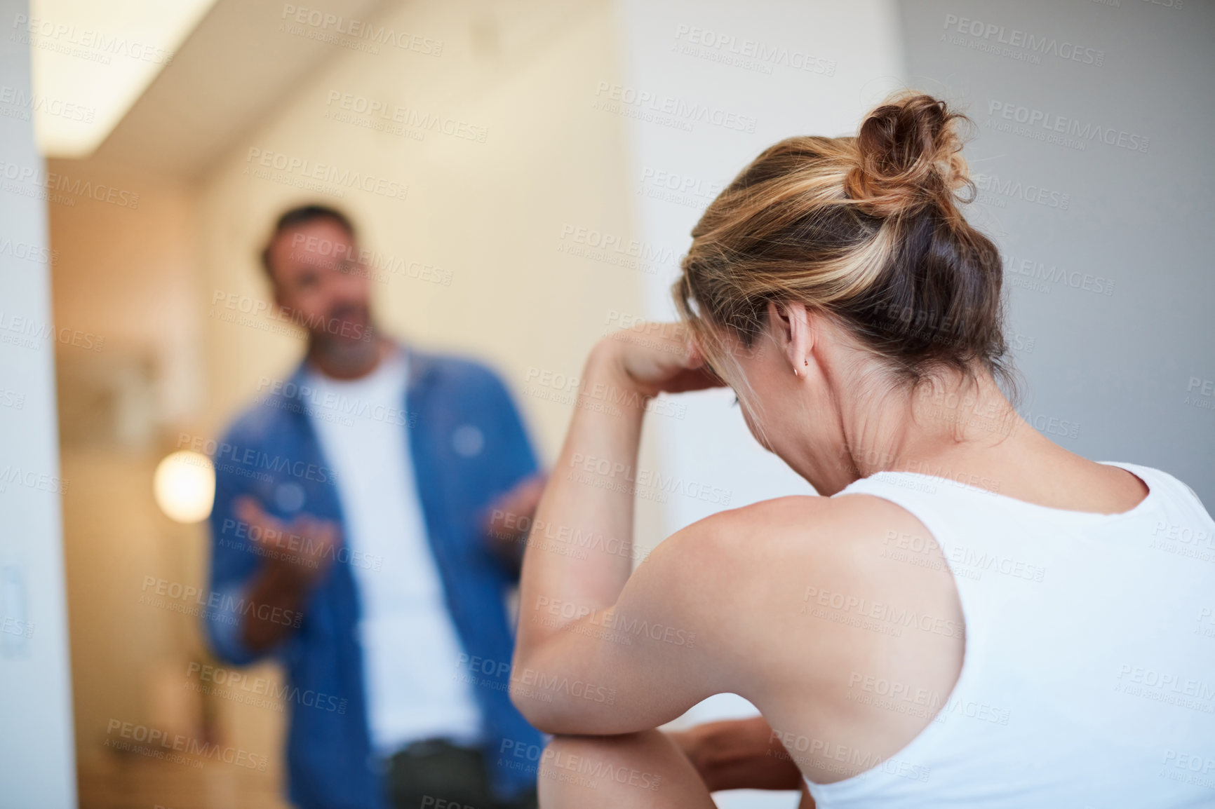 Buy stock photo Rearview shot of an unrecognizable young woman looking distressed with her husband in the background