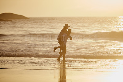 Buy stock photo Shot of a man piggybacking his girlfriend on the beach