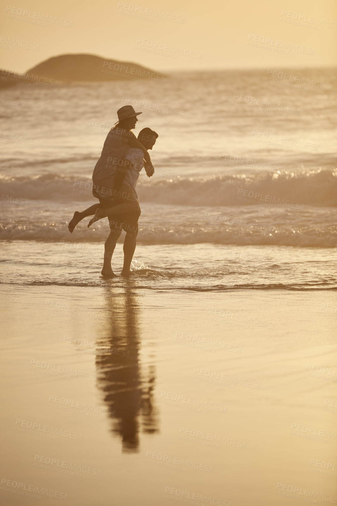 Buy stock photo Shot of a man piggybacking his girlfriend on the beach