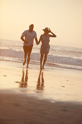 Buy stock photo Shot of a mature couple running on the beach