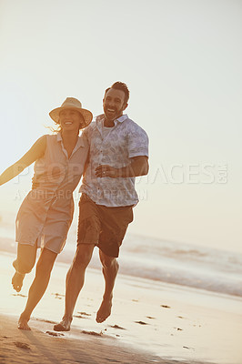 Buy stock photo Shot of a mature couple running on the beach