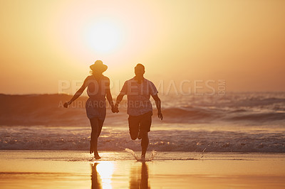 Buy stock photo Shot of a mature couple running on the beach