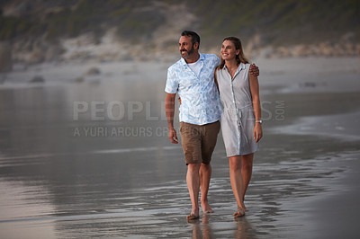 Buy stock photo Shot of an affectionate mature couple taking a walk on the beach