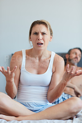 Buy stock photo Portrait of an attractive young woman looking confused  in the bedroom with her husband in the background