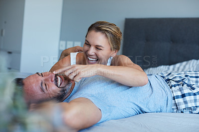 Buy stock photo Cropped shot of an attractive young woman being playful with her husband while lying in bed in the morning