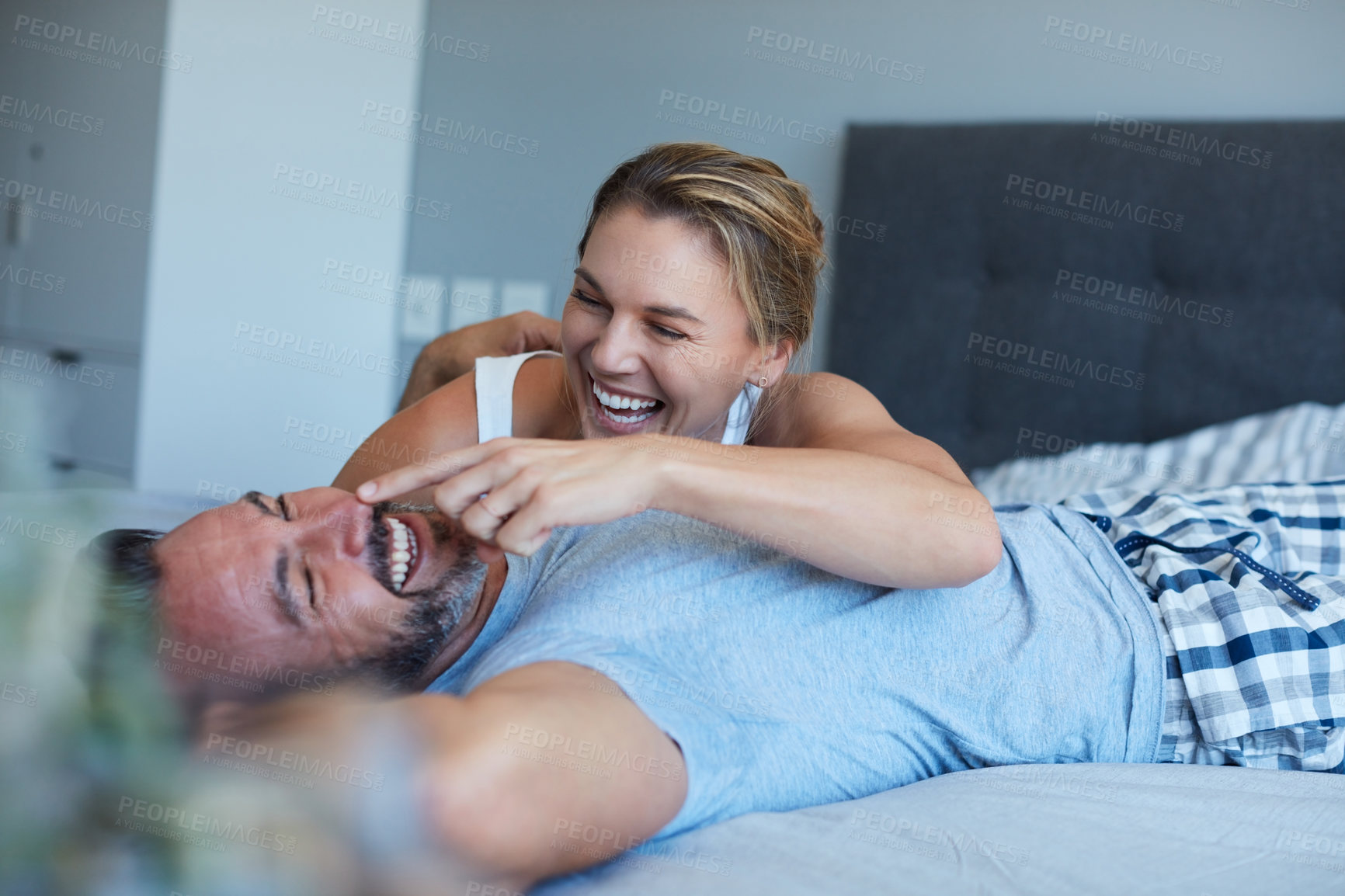 Buy stock photo Cropped shot of an attractive young woman being playful with her husband while lying in bed in the morning