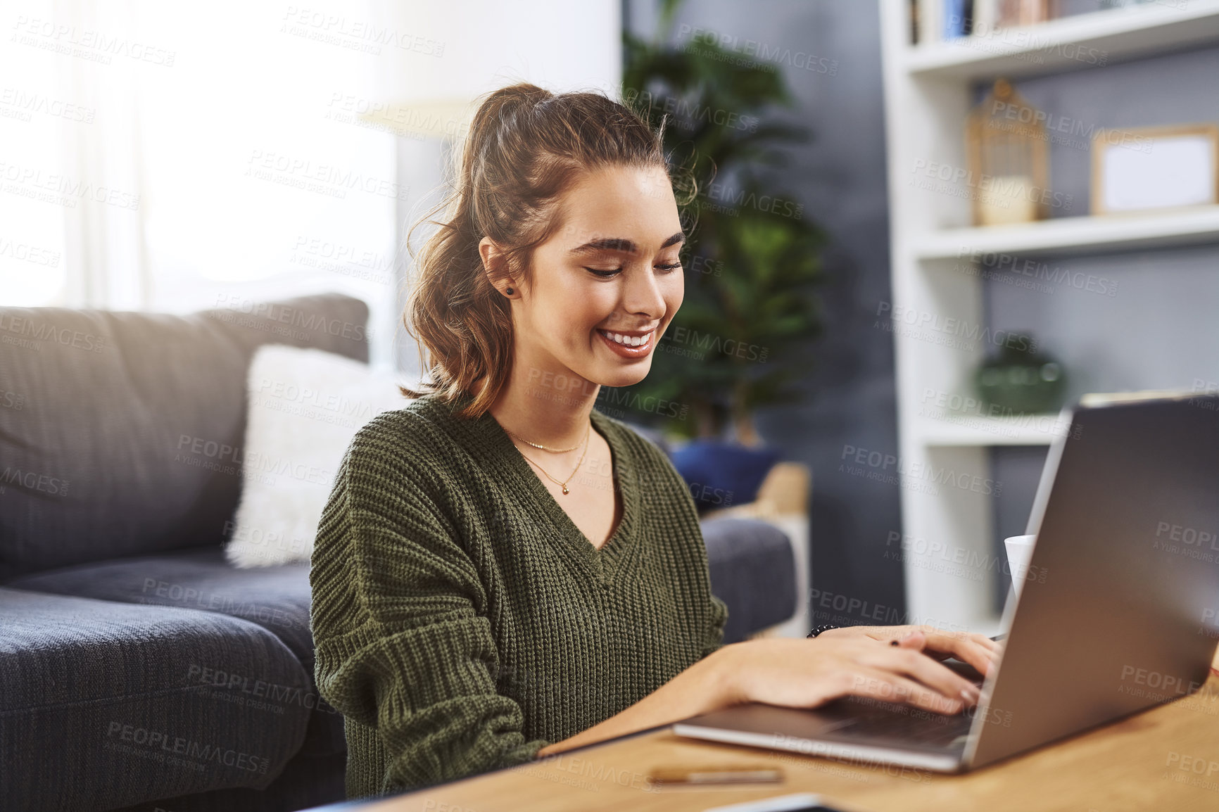 Buy stock photo Shot of a beautiful young woman using a laptop while relaxing at home during the day
