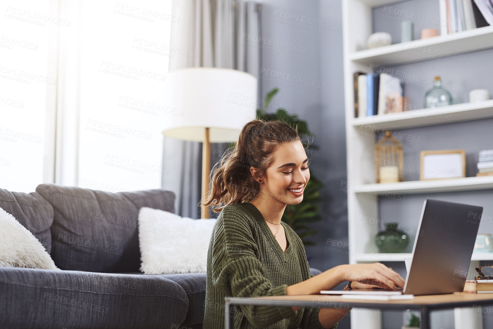 Buy stock photo Shot of a beautiful young woman using a laptop while relaxing at home during the day