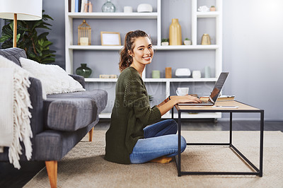Buy stock photo Full length shot of a beautiful young woman sitting on the floor and using her laptop while relaxing at home