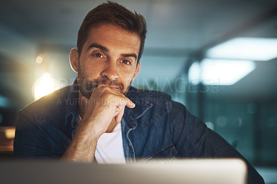 Buy stock photo Portrait of a handsome young businessman working late at night on his computer in a modern office