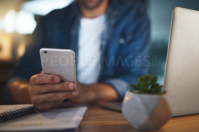 Buy stock photo Shot of an unrecognisable businessman using his cellphone while sitting at his desk in a modern office