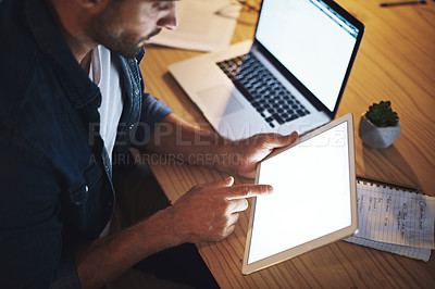 Buy stock photo Shot of a handsome young businessman working late at night on his tablet in a modern office