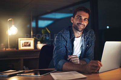 Buy stock photo Portrait of a handsome young businessman smiling while working late at night in a modern office