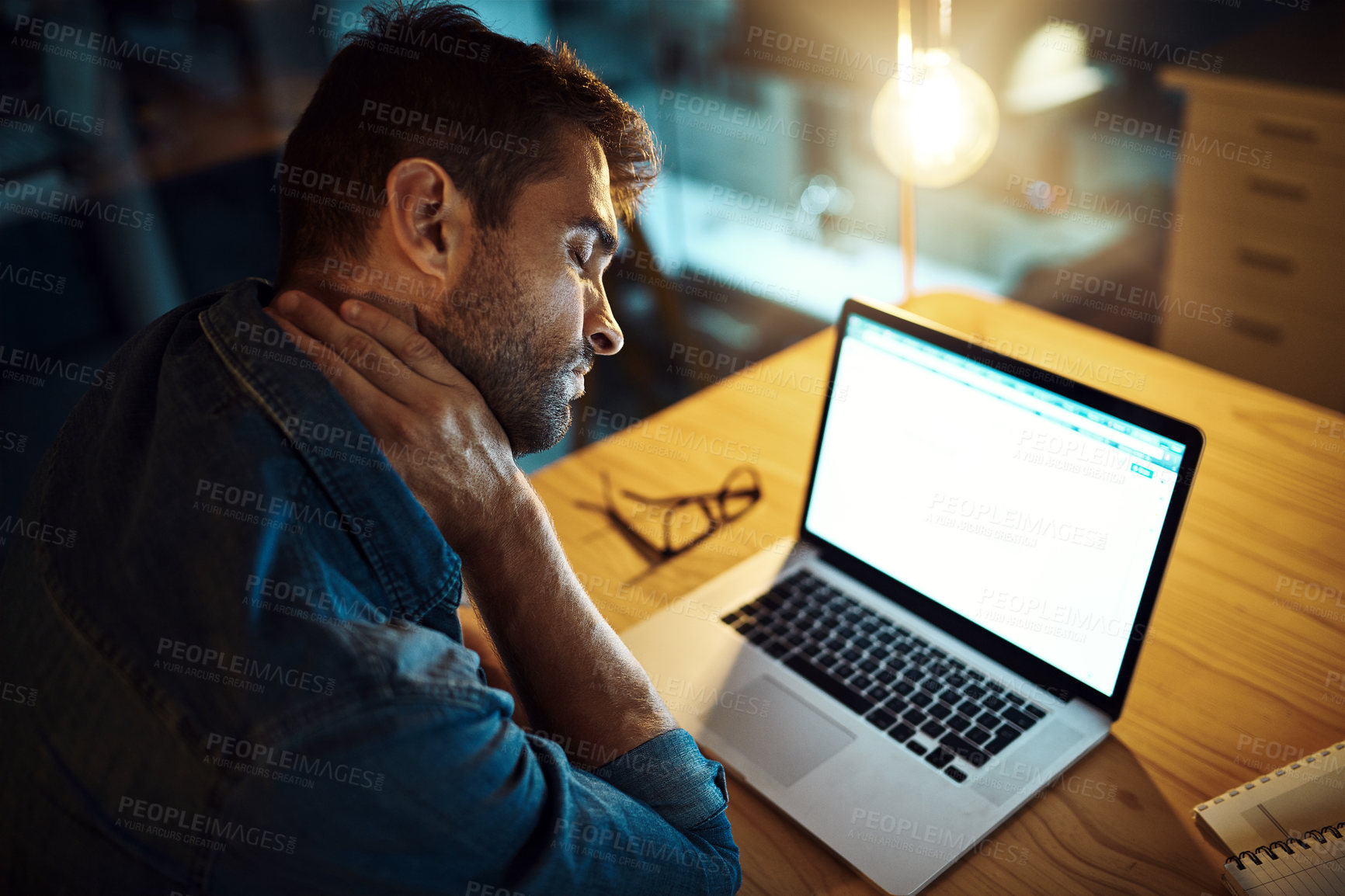 Buy stock photo Man, laptop and neck pain at night in office with fatigue, stress and muscle injury at startup. Person, computer and inflammation with burnout, tired and overtime with deadline at creative agency