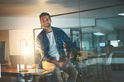 Buy stock photo Shot of a handsome young businessman working late at night in a modern office