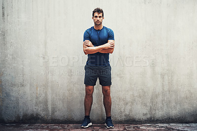 Buy stock photo Portrait of a sporty young man standing against a grey wall while exercising outdoors