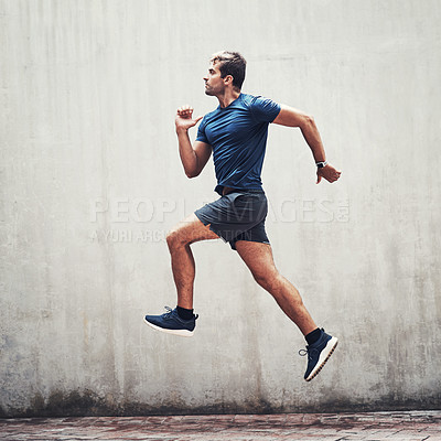 Buy stock photo Shot of a sporty young man running against a grey wall outdoors