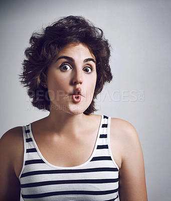 Buy stock photo Studio portrait of an attractive young woman making a funny face while standing against a grey background