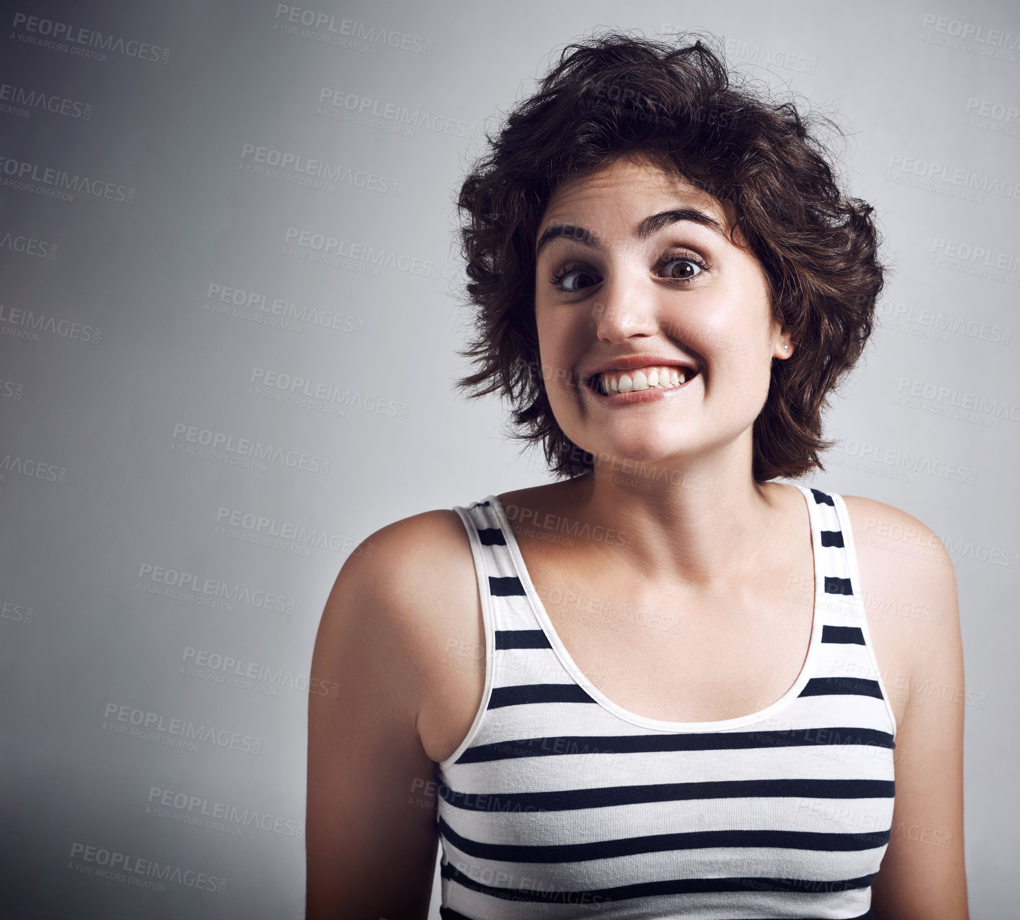 Buy stock photo Studio shot of an attractive young woman grinning broadly while standing against a grey background