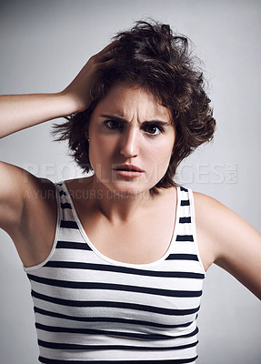 Buy stock photo Studio portrait of an attractive young woman looking shocked while standing against a grey background