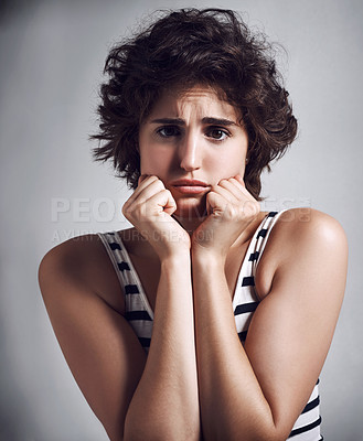 Buy stock photo Studio portrait of an attractive young woman looking scared while standing against a grey background