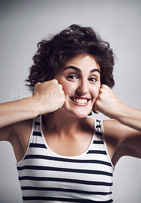 Buy stock photo Studio portrait of an attractive young woman making a funny face with her fists against a grey background