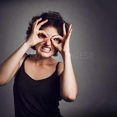 Buy stock photo Studio portrait of an attractive young woman making a funny face while standing against a grey background