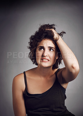 Buy stock photo Studio shot of an attractive young woman looking worried while standing against a grey background