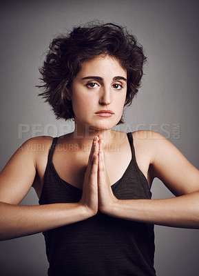 Buy stock photo Studio portrait of an attractive young woman with her hands in prayer position against a grey background