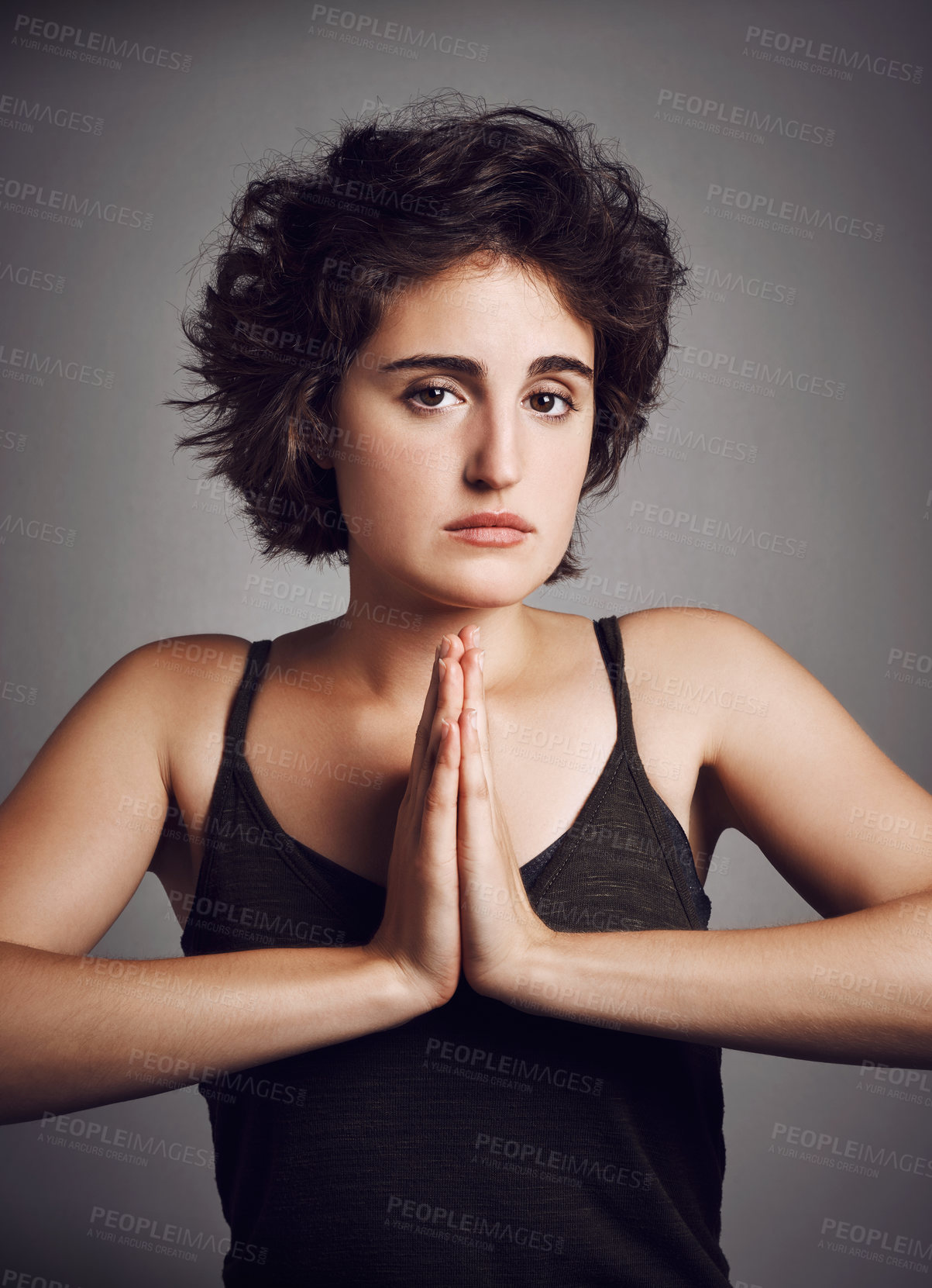 Buy stock photo Studio portrait of an attractive young woman with her hands in prayer position against a grey background
