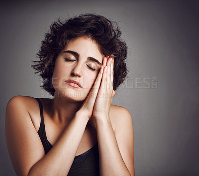 Buy stock photo Studio shot of an attractive young woman sleeping on her hands against a grey background